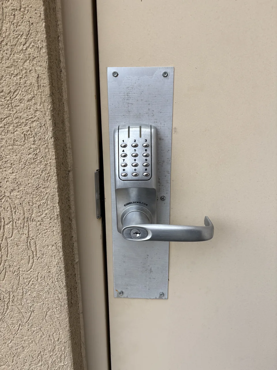 Push-button keypad lock and lever handle fitted to a commercial door